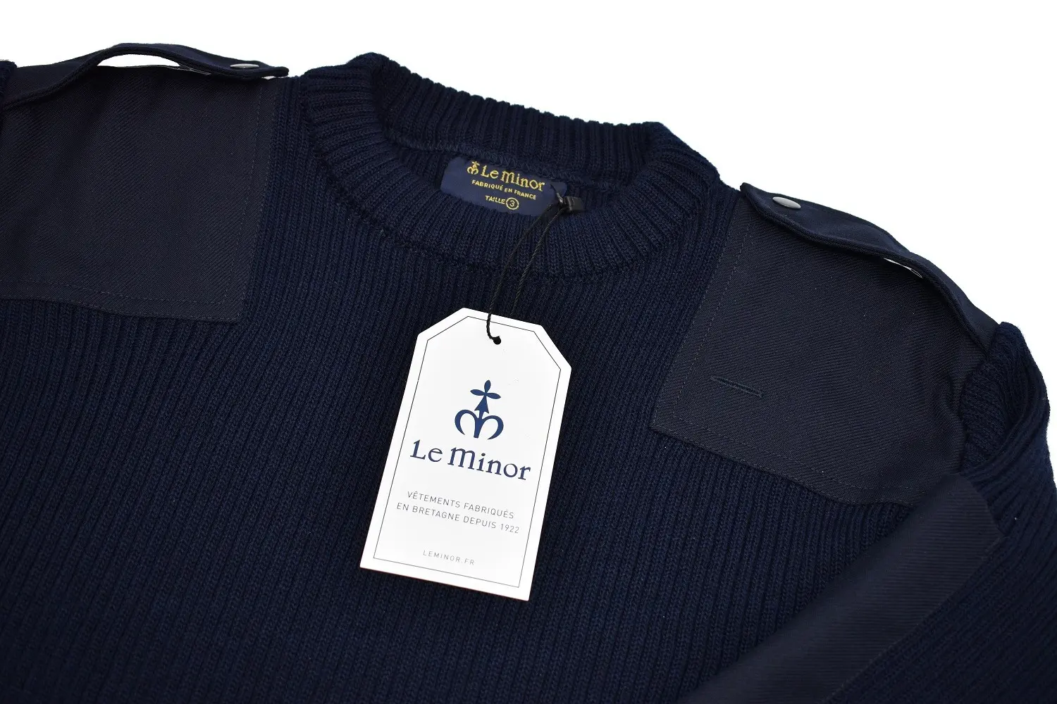 Pull en maille bleu marine Le Minor avec étiquette grande tag suspendue blanc et fleuron gris, col ras, épaulettes et poches.
